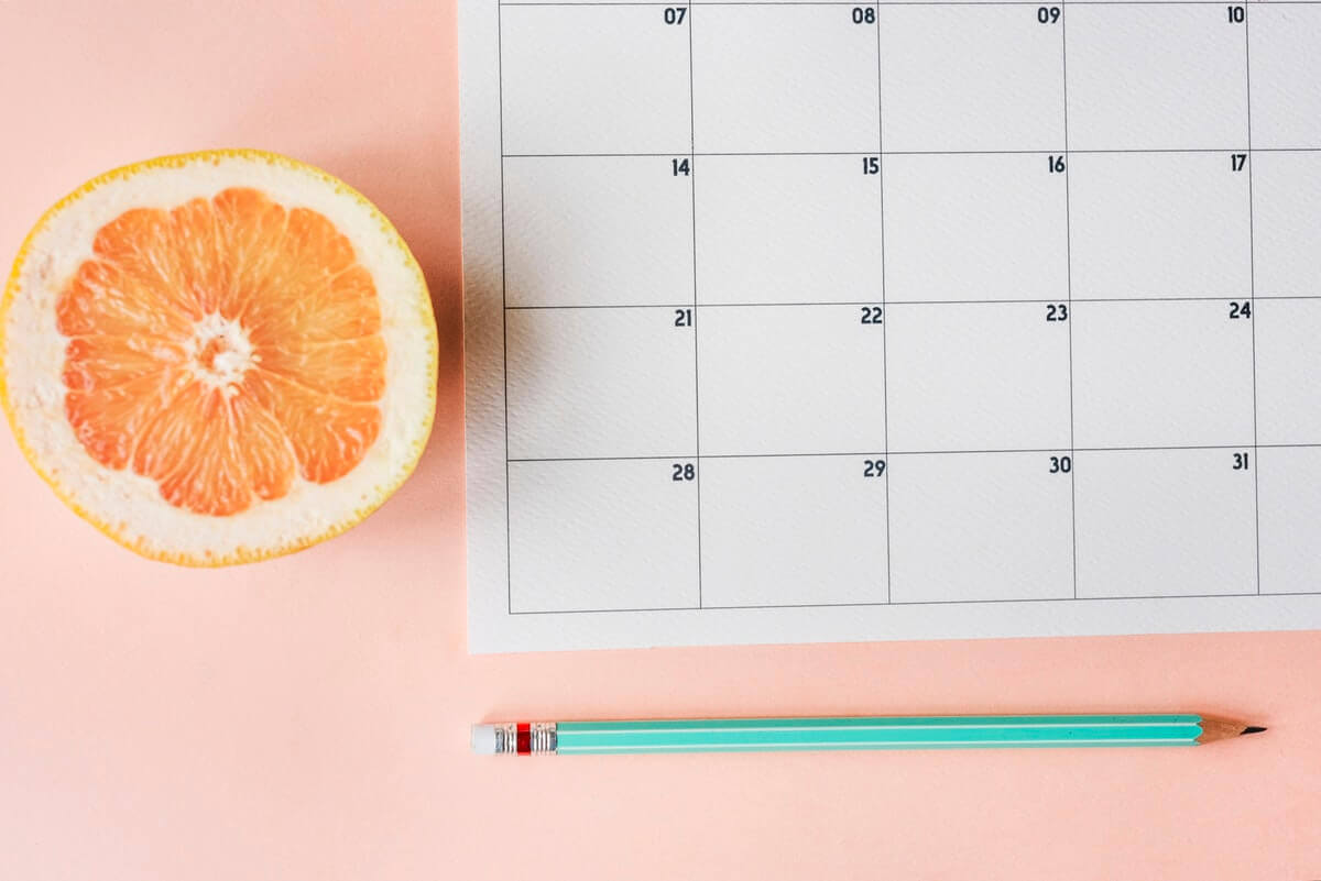 Calendar with an orange beside representing summer